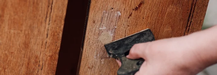 Person schleift Holzkommode mit Schleifpapier